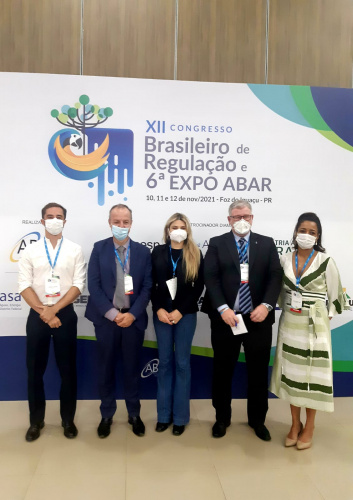 Participantes da palestra em frente ao banner do evento.