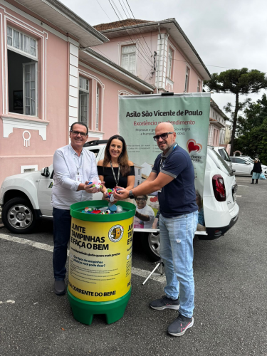 Três servidores posam com a doação de tampinhas realizada pela Agepar